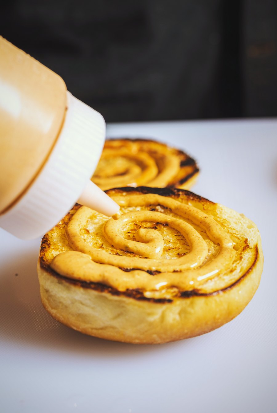 Sauce piped in a spiral onto a bun